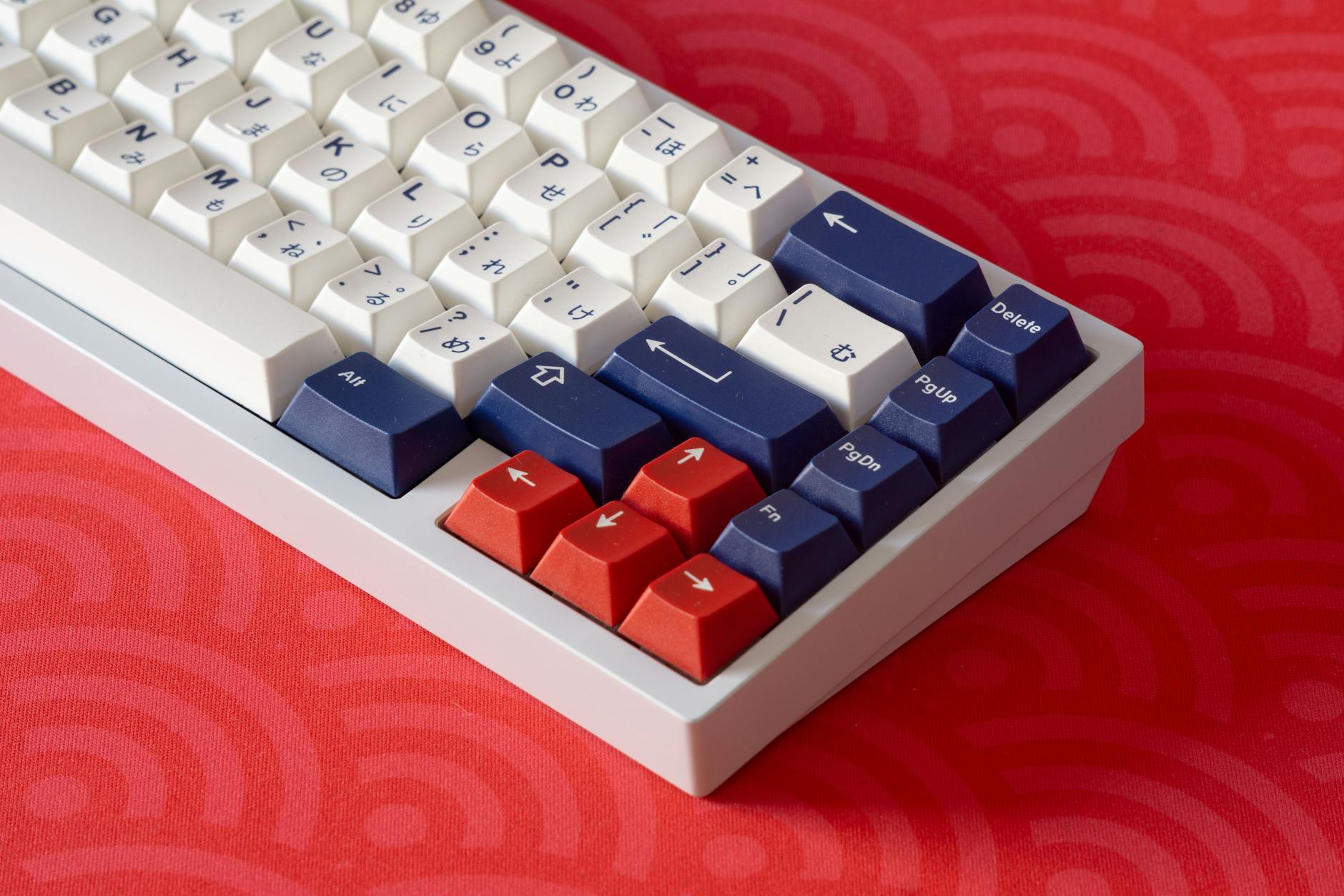 Close-up of a white and red mechanical keyboard with blue keys on a vibrant red surface.